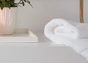 envello white cotton Hand Towel folded and resting on bathroom vanity next to potted plant