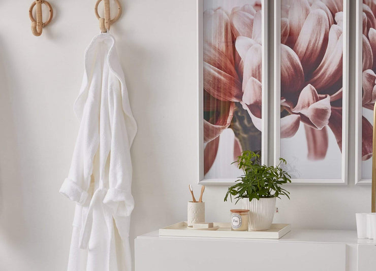 envello Classic Plush Cotton Bathrobe hanging on a bamboo hook with a large picture of pink flowers.